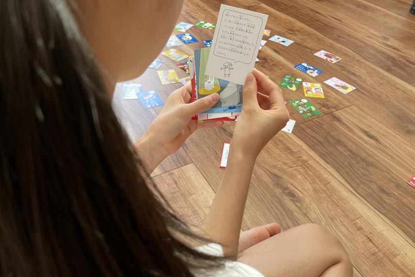 生理カルタの絵札の裏に書かれている生理の豆知識を読む子ども
